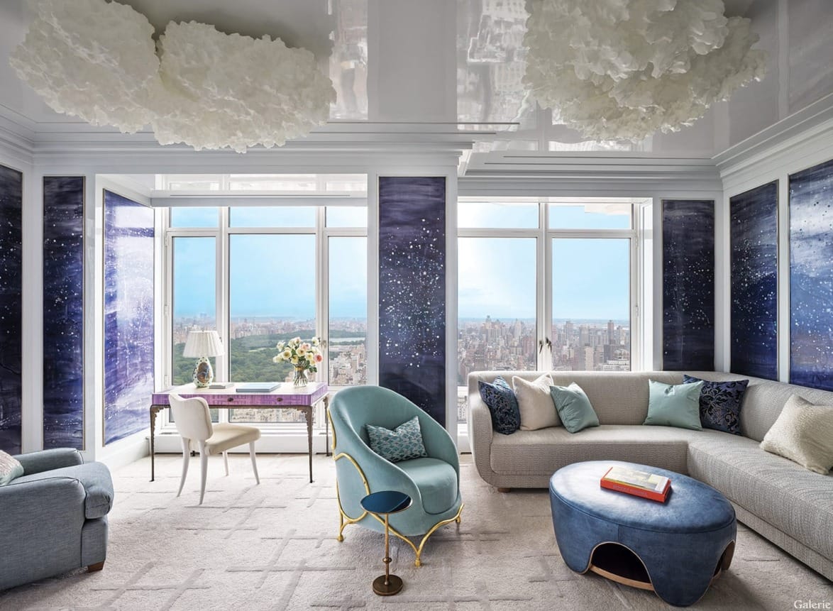 Luxurious modern living room with blue and white accents, featuring a large window overlooking a cityscape.