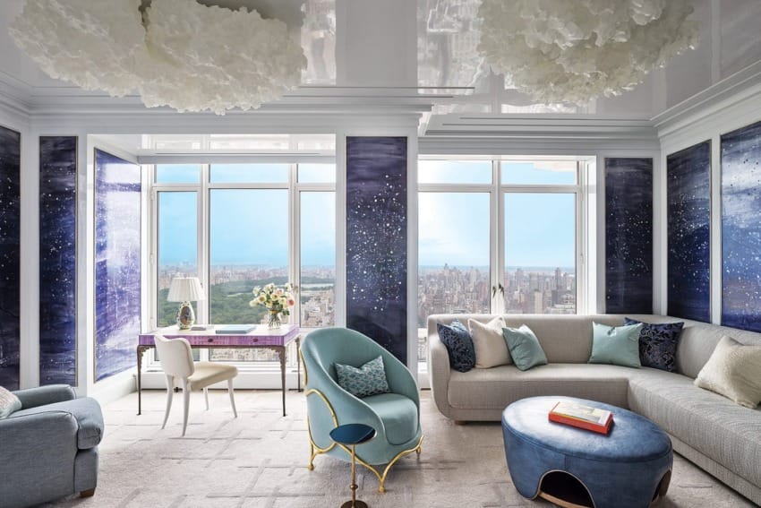 Luxurious modern living room with blue and white accents, featuring a large window overlooking a cityscape.