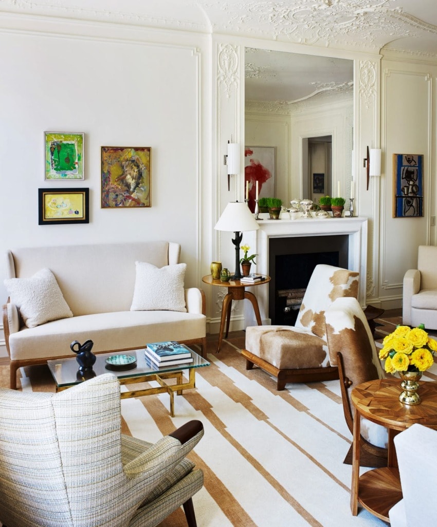 Elegant living room with modern furniture, decorative artworks, and a fireplace, featuring neutral tones and wood accents.