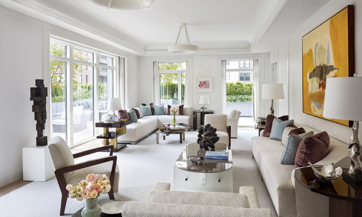 Modern living room with large windows, white sofas, contemporary art, and decorative sculptures.