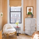 Cozy room with patterned wallpaper, elegant chair, small table with flowers, abstract art, and a wavy dresser.