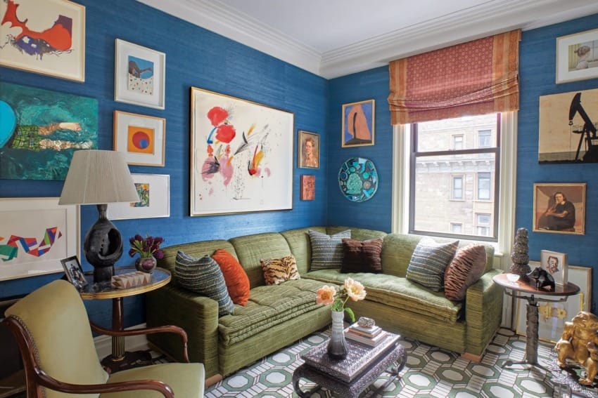 Eclectic living room with vibrant blue walls, green sofa, patterned rug, and diverse artwork displays.