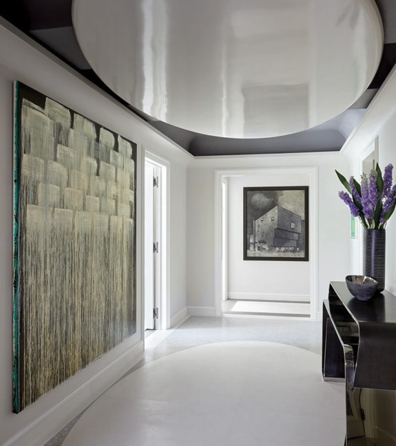 Modern hallway featuring abstract artwork, a sleek black console table, and fresh purple flowers in a vase.