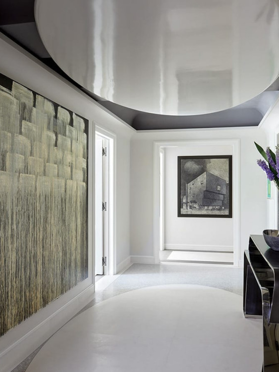 Modern hallway featuring abstract artwork, a sleek black console table, and fresh purple flowers in a vase.