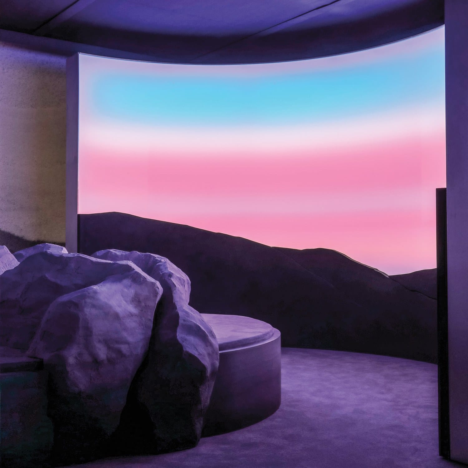 Modern interior with large rocks and a curved wall displaying a gradient sky of pink and blue hues, creating a serene ambiance.