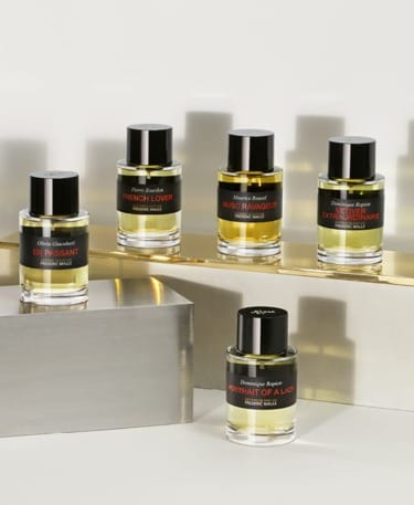 Five perfume bottles from Frederic Malle, elegantly displayed on a reflective surface.