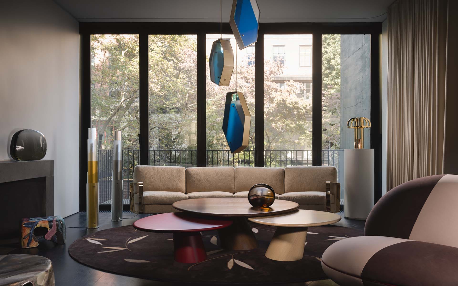 Modern living room with large windows, a beige sofa, abstract pendant lights, round coffee table, and contemporary decor.