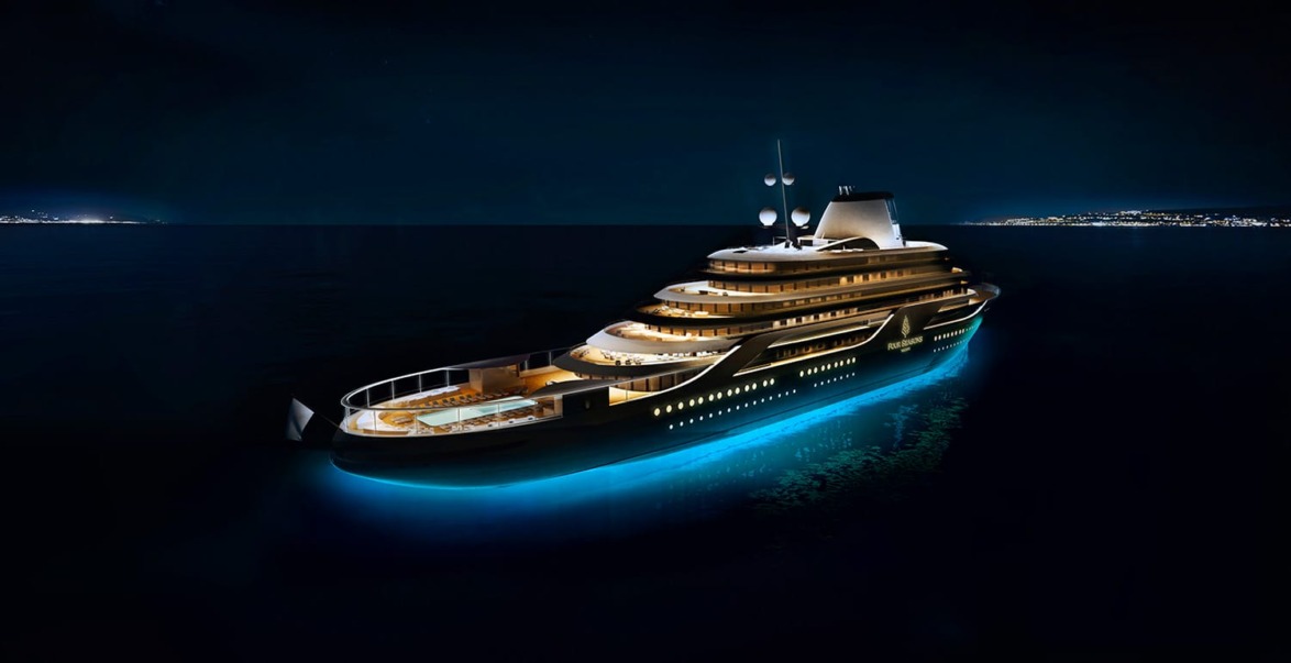 illuminated luxury yacht sailing at night with city lights in the distance