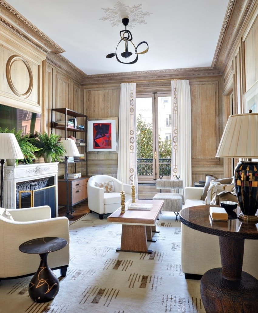 Elegant living room with wooden paneled walls, modern chandelier, white sofas, and large windows with curtains.