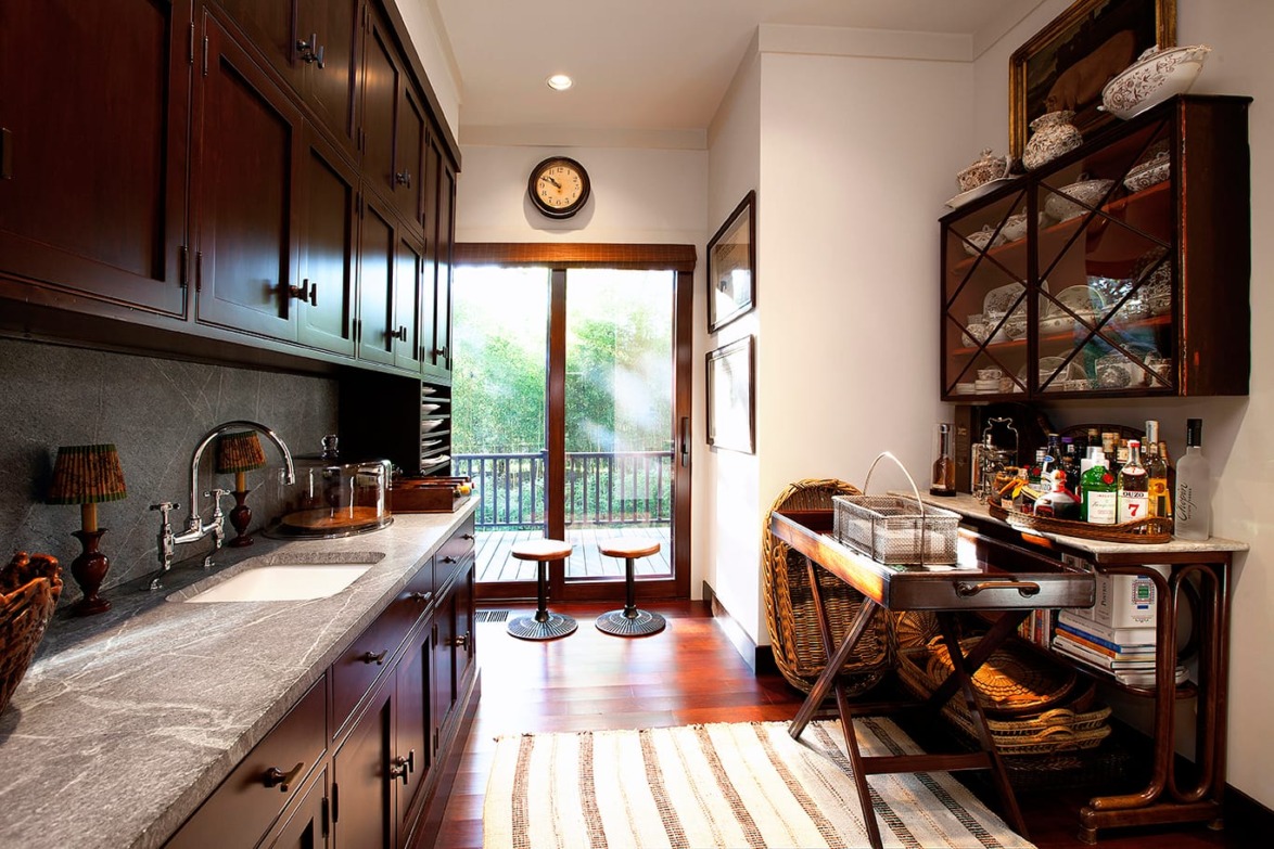 Cozy kitchen with wooden cabinets, a stone countertop, and a view of greenery through a glass door.