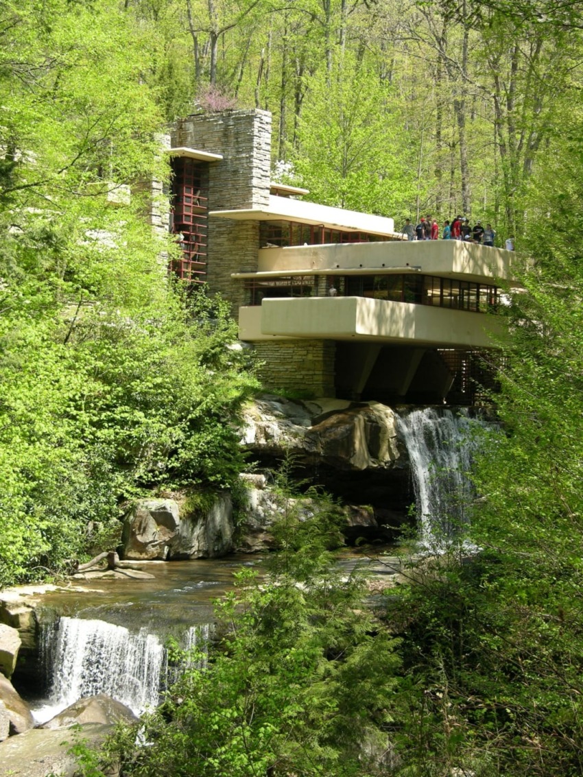 Fallingwater, a house designed by architect Frank Lloyd Wright, set amidst lush greenery and a flowing waterfall.