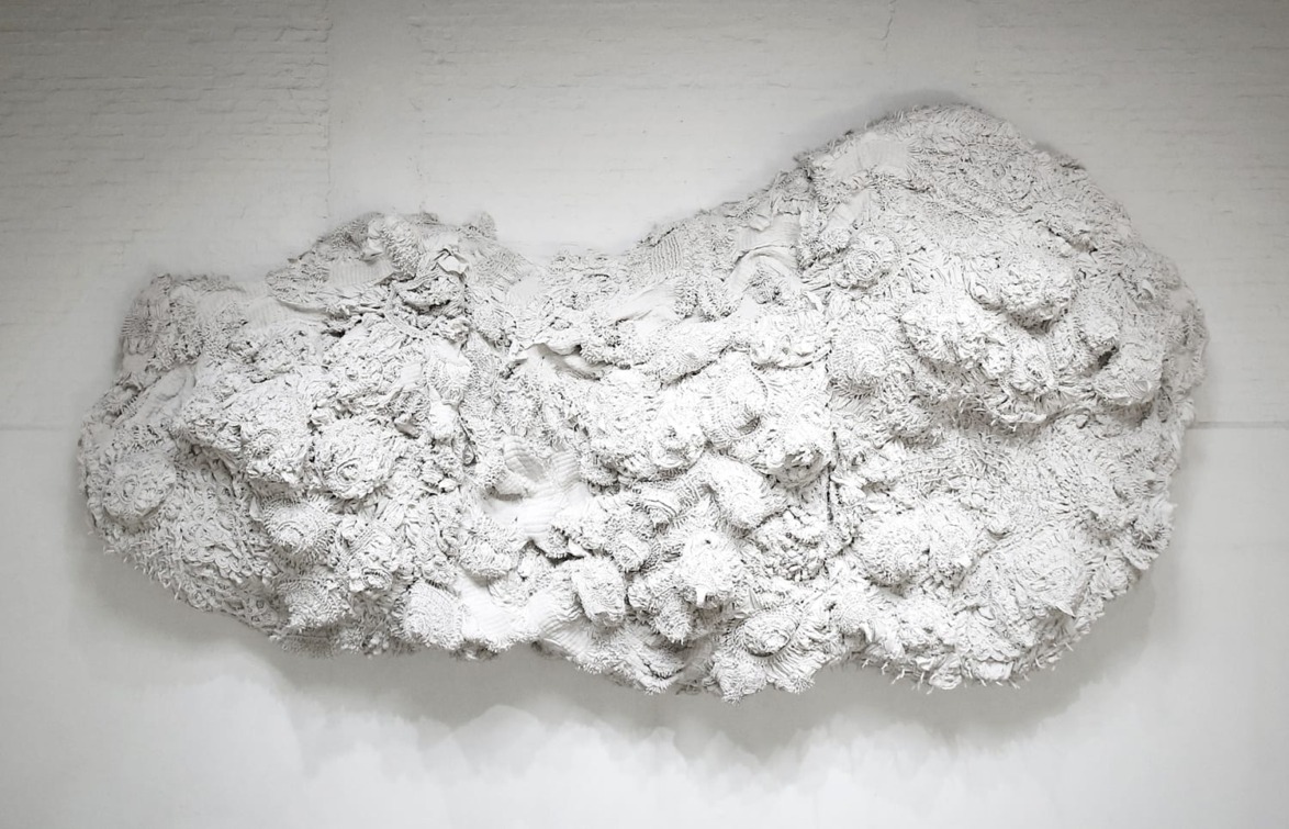 Textured white cloud-like sculpture mounted on a white wall