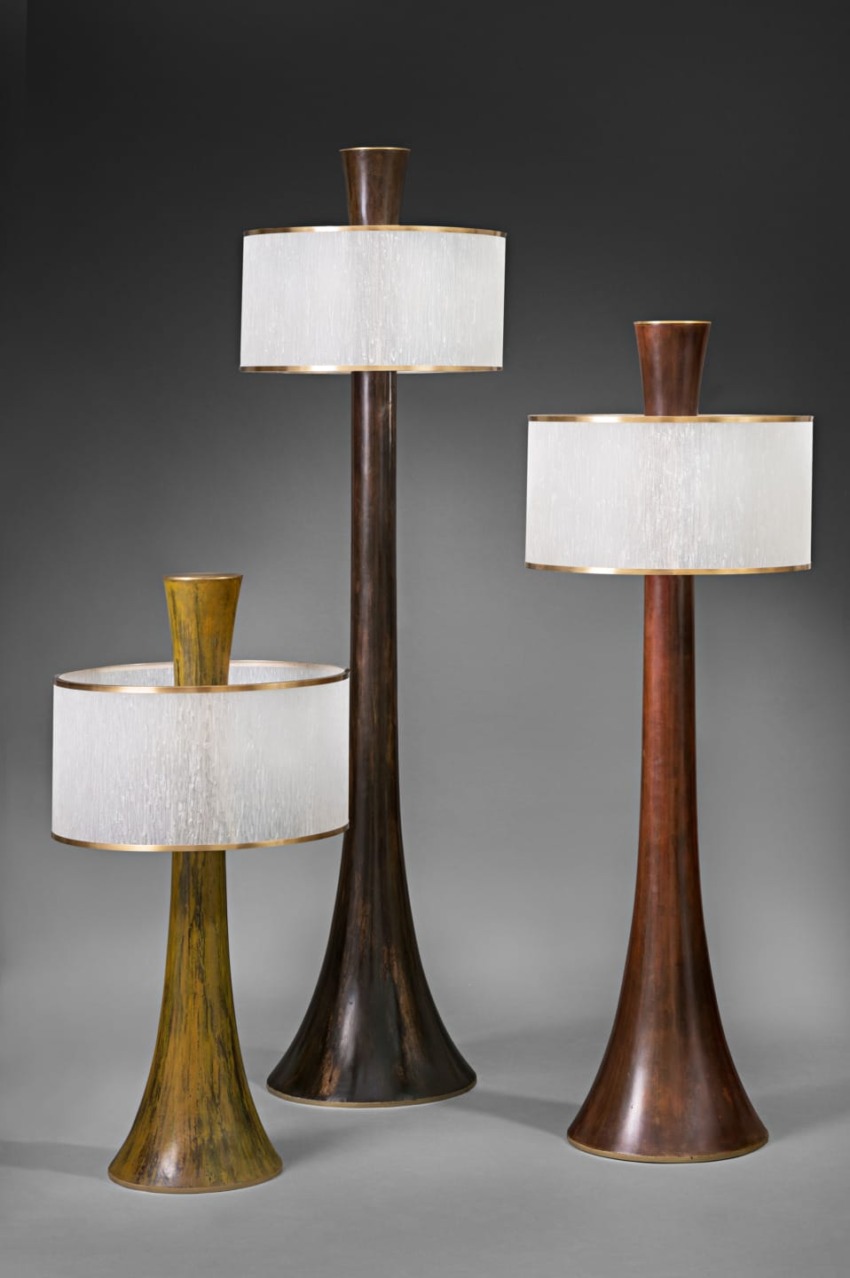 Three elegant, cone-shaped floor lamps with wide white shades on a dark gradient background.