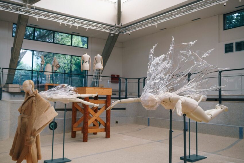 Artistic mannequins in dynamic poses with transparent extensions in a modern gallery setting.