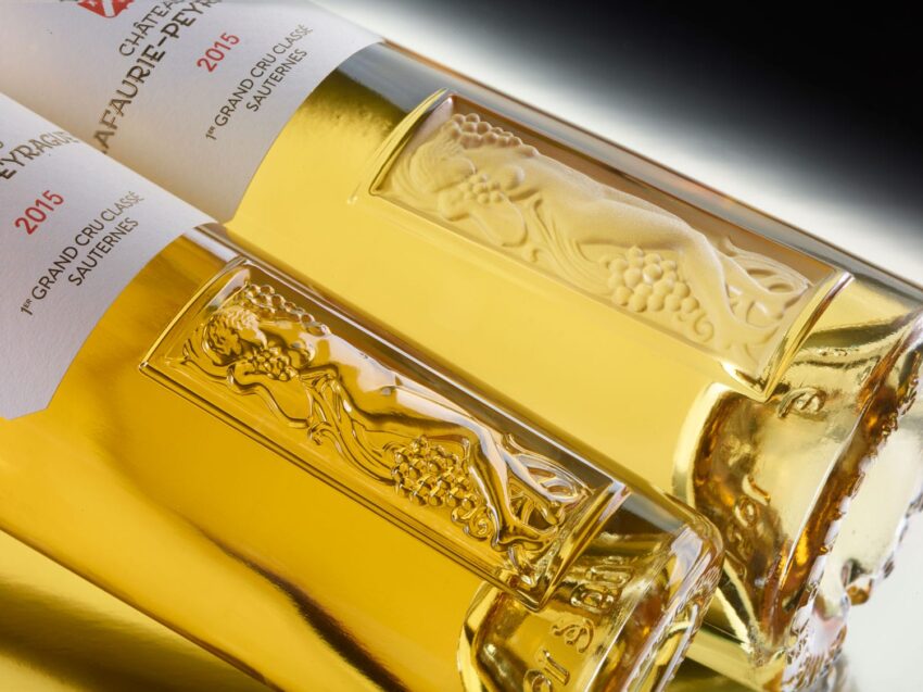 Two ornate wine bottles lying sideways, featuring embossed grapevine designs and labels indicating 2015 vintage.