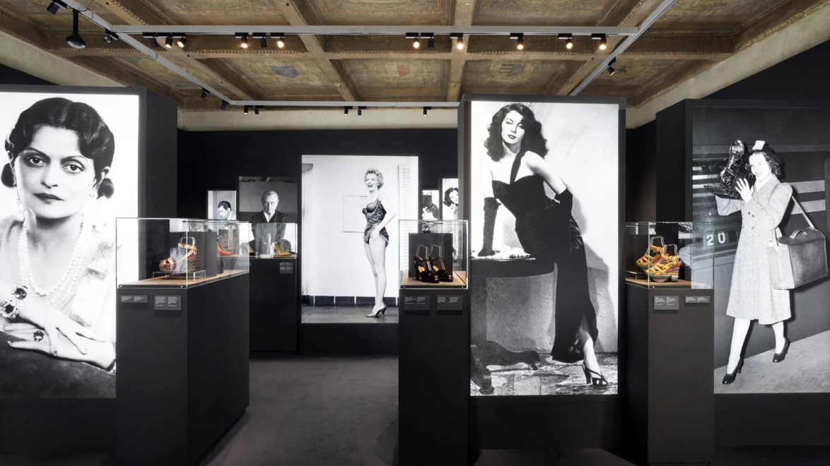 Museum exhibit featuring vintage fashion and footwear displays with large black and white photos of stylish individuals on walls.