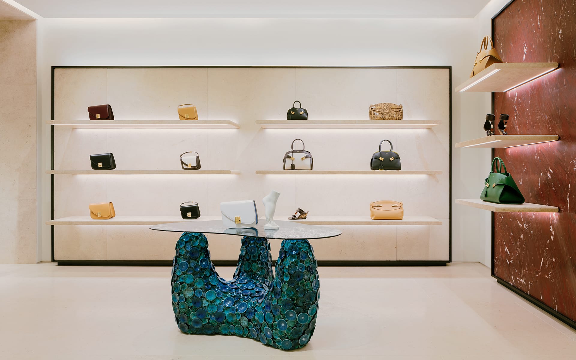 Luxurious store interior showcasing designer handbags on shelves with a unique sculptural table in the center.