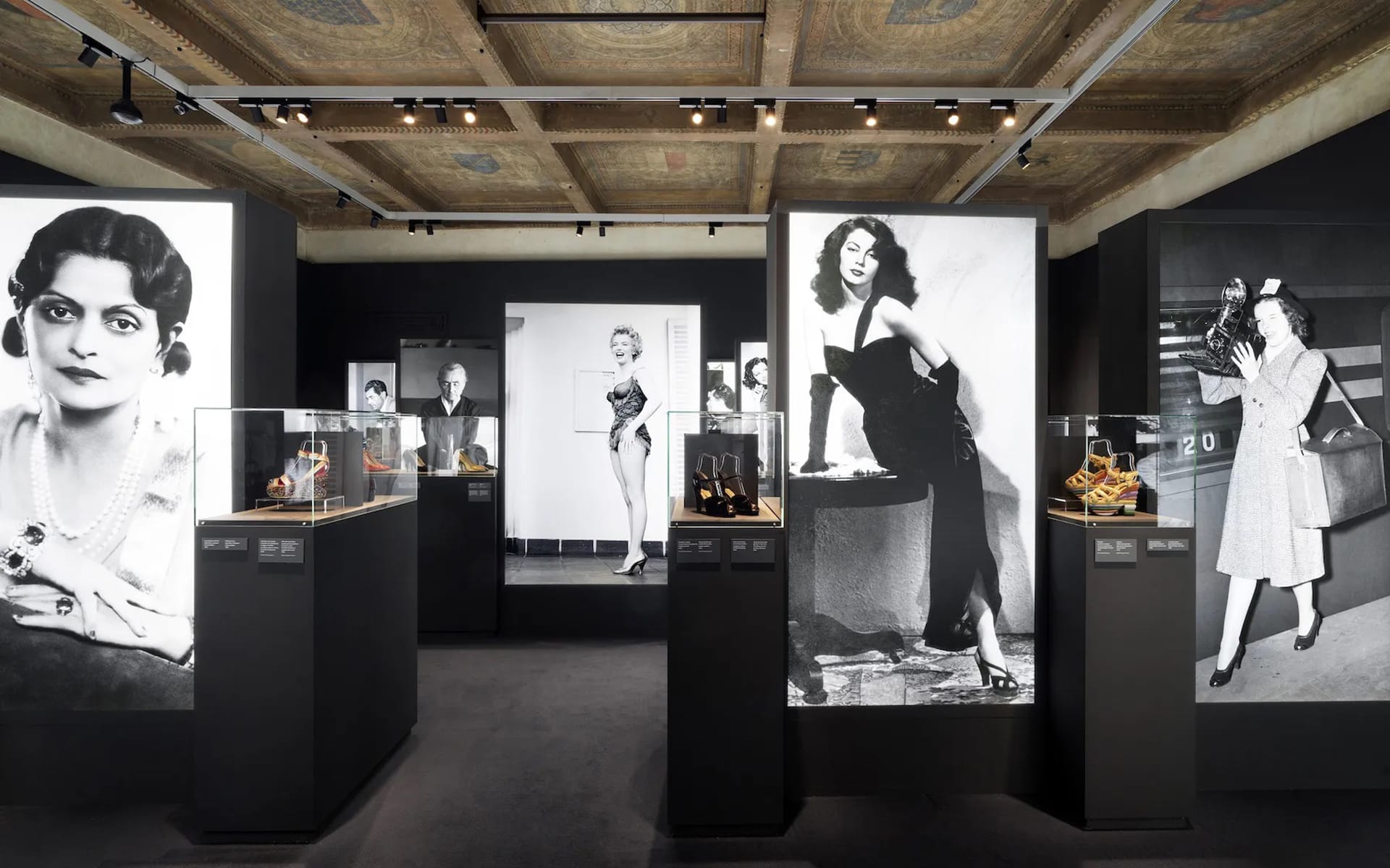 Museum exhibit featuring vintage fashion and footwear displays with large black and white photos of stylish individuals on walls.