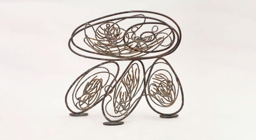 Abstract metal sculpture with interwoven circular and elliptical shapes on a white background.