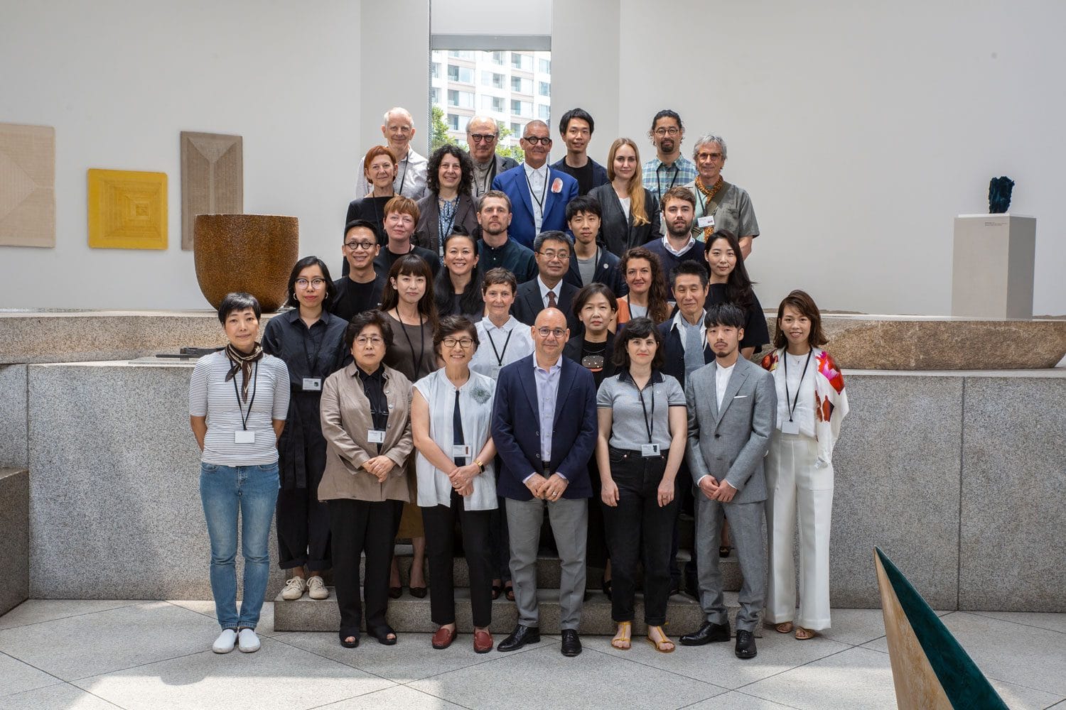 Group of people posing for a photo indoors with artwork displayed on the walls in the background.