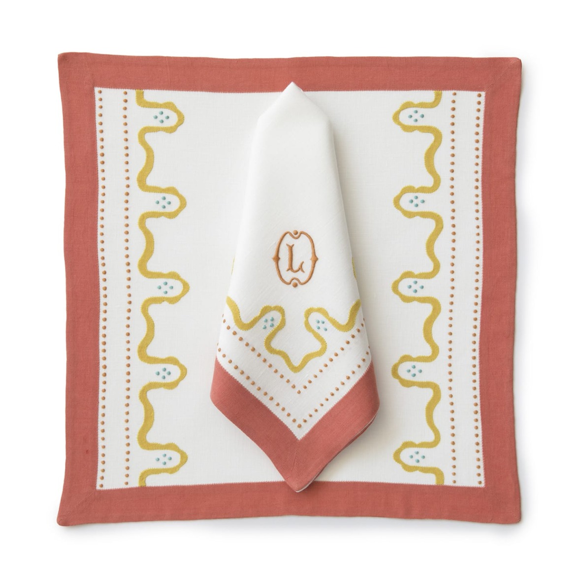 Decorative napkin set with intricate yellow and green embroidery on a white background, bordered by a rich terracotta trim.