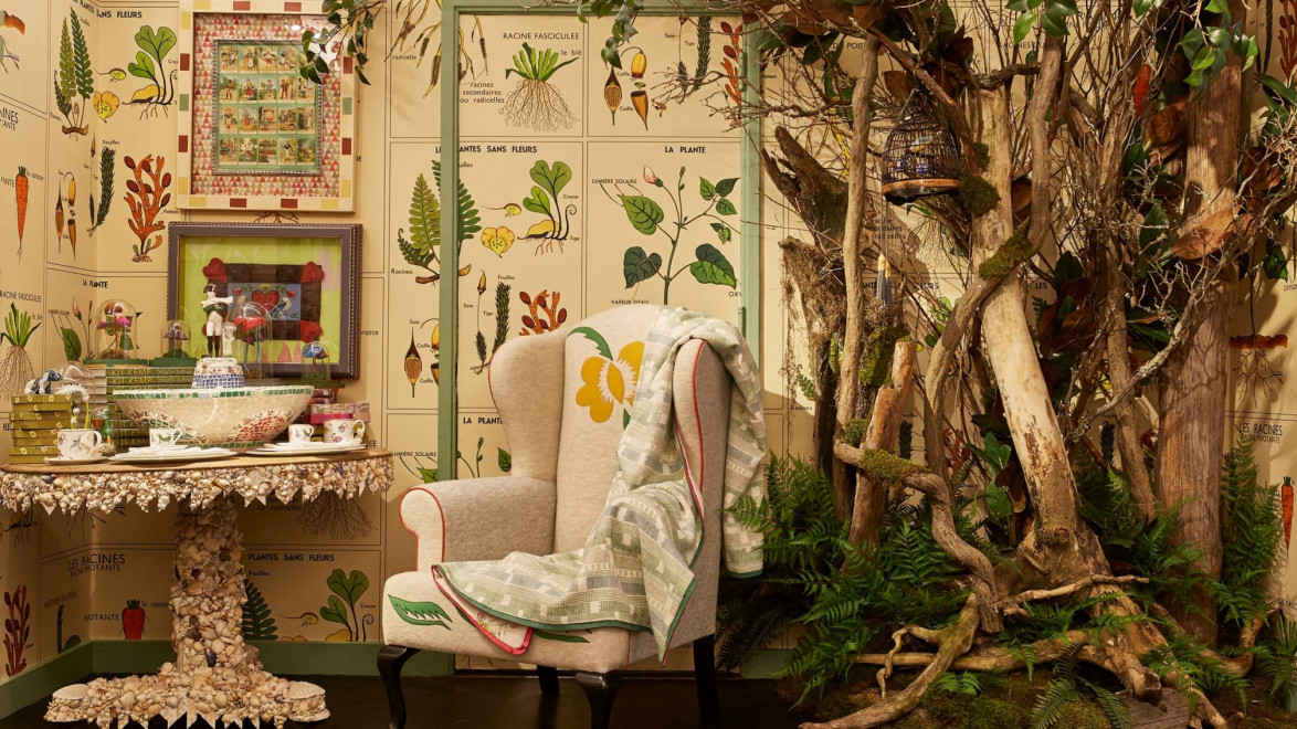 Cozy room with an armchair, a shell-covered table, botanical wallpaper, and a rustic wooden decor with greenery.