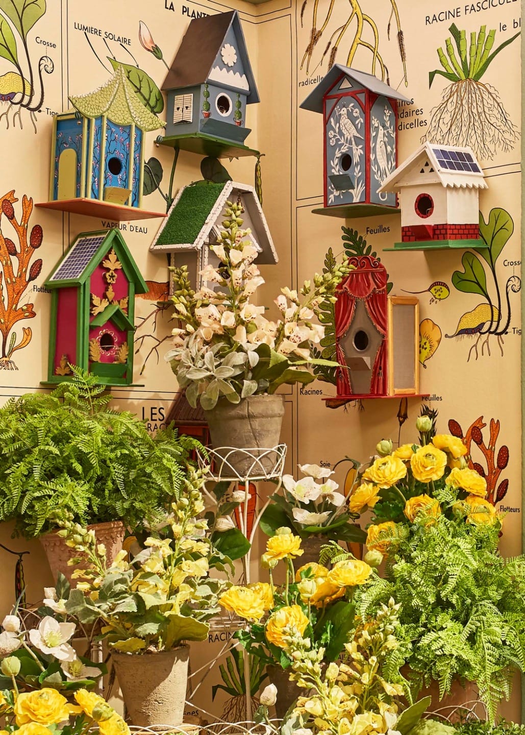 Colorful birdhouses and vibrant flowers arranged in a botanical-themed display.