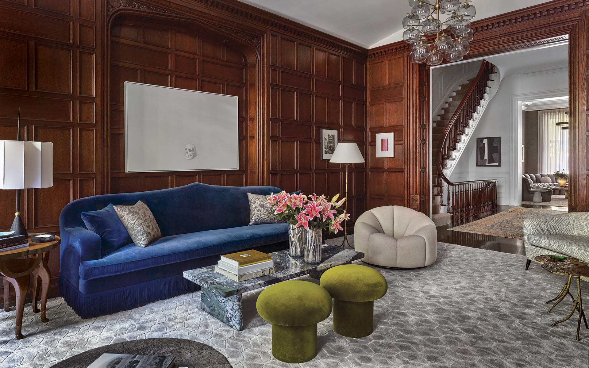 Luxurious living room with dark wood paneling, velvet blue sofa, modern art, and elegant floral decor.