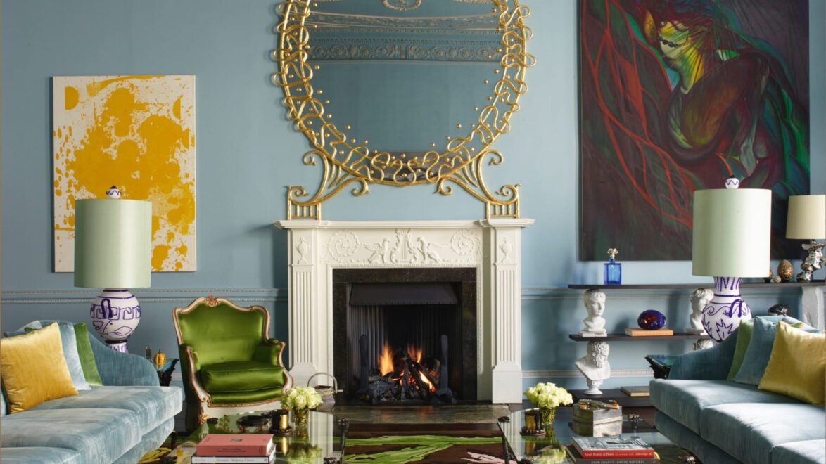 Luxurious living room with ornate mirror, colorful paintings, and vibrant furniture surrounding a cozy fireplace.