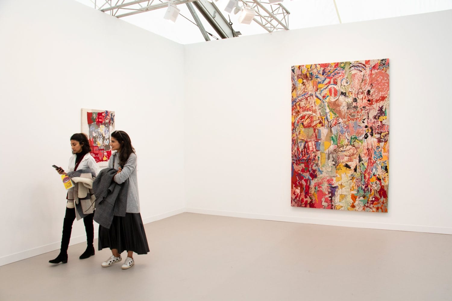 Women viewing colorful abstract paintings in a modern art gallery.