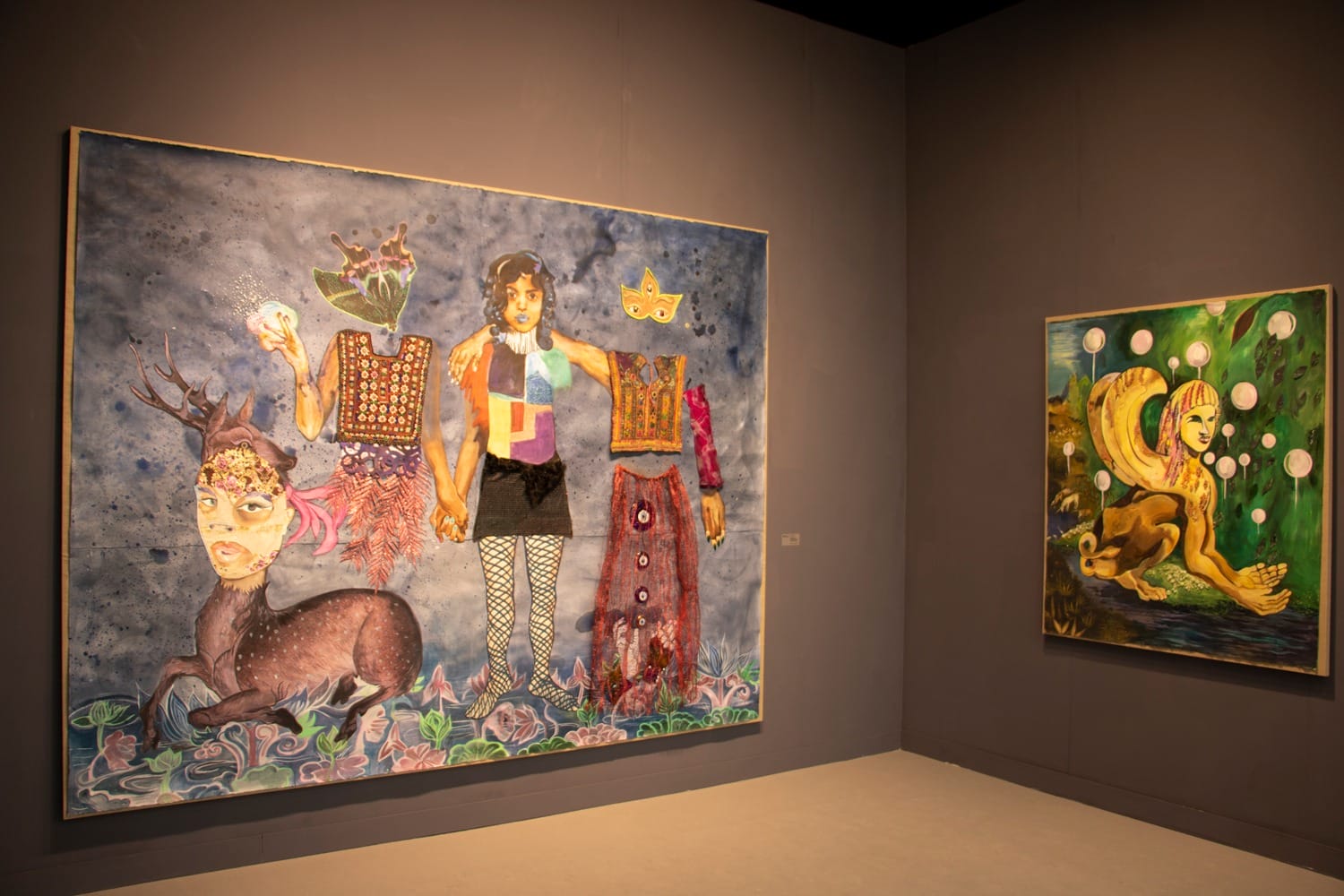 Colorful surreal paintings featuring fantastical creatures displayed on a dark gallery wall.