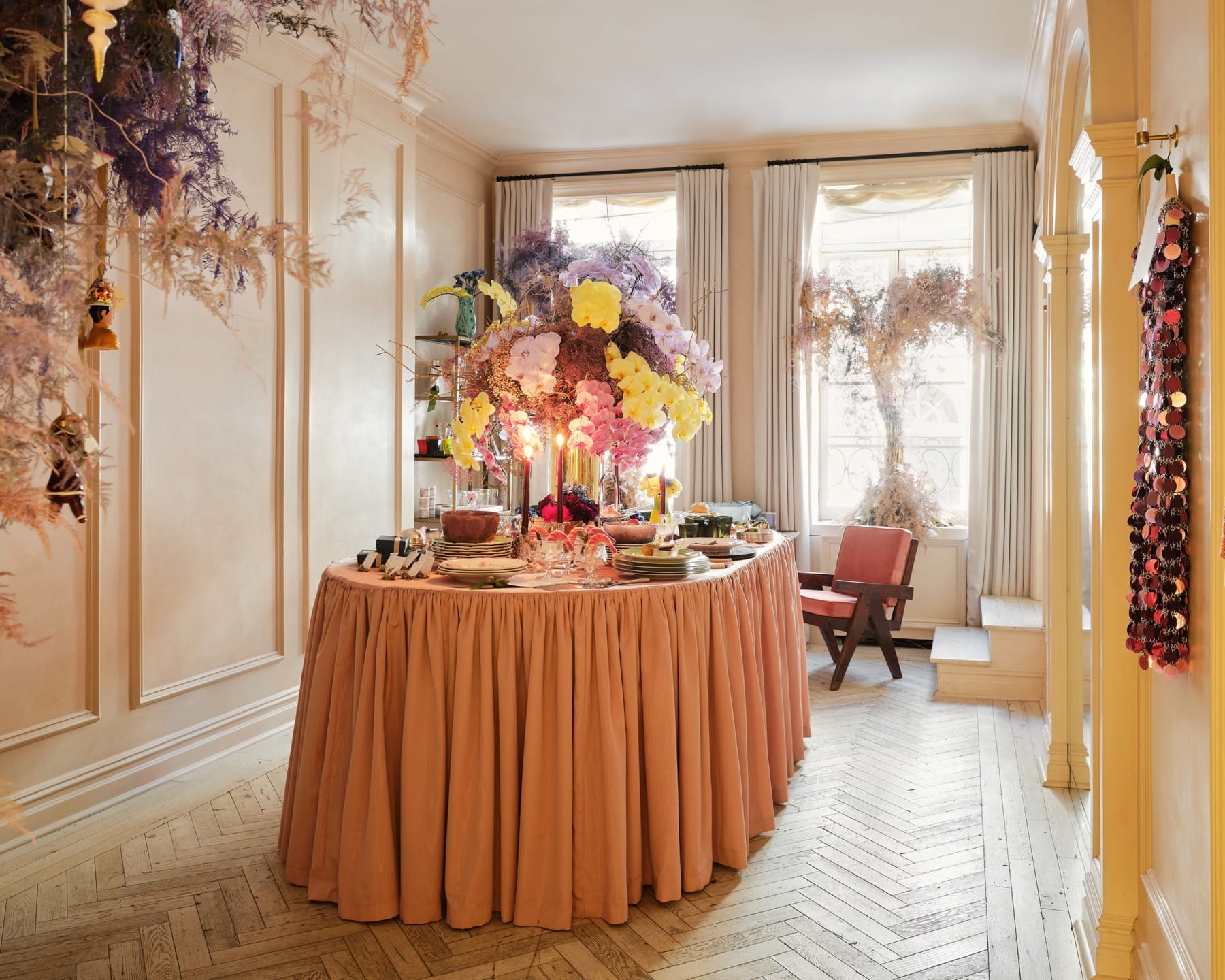 Elegant dining room with a round table adorned with floral centerpieces, surrounded by soft lighting and sophisticated decor.
