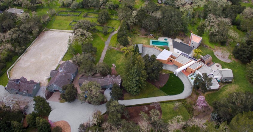 Aerial view of a large estate with multiple buildings, a swimming pool, and lush greenery.