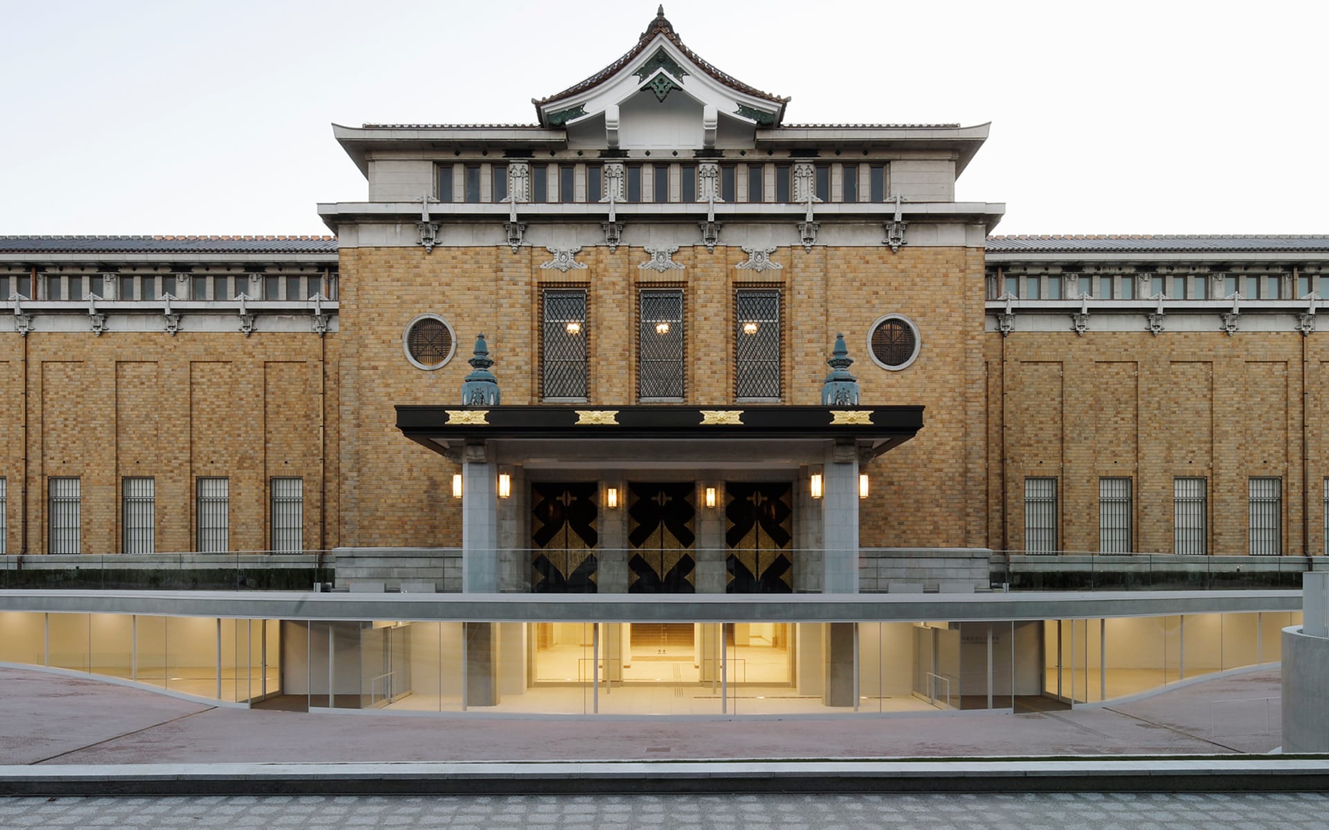 Exterior view of a historical building with traditional architectural elements and modern entrance, featuring brickwork and round windows.