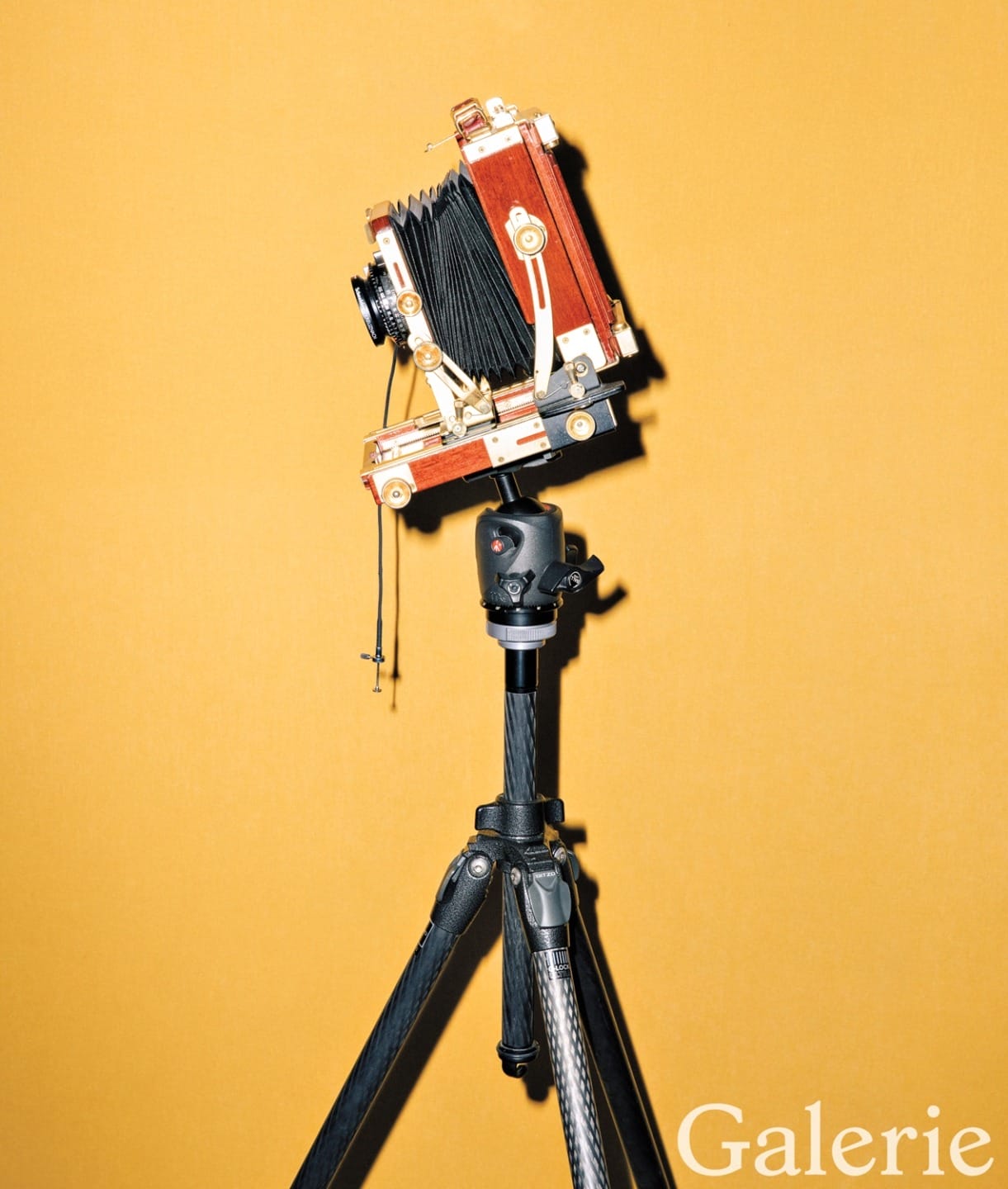 Vintage wooden camera on a tripod against a vibrant orange background with "Galerie" text in the corner.
