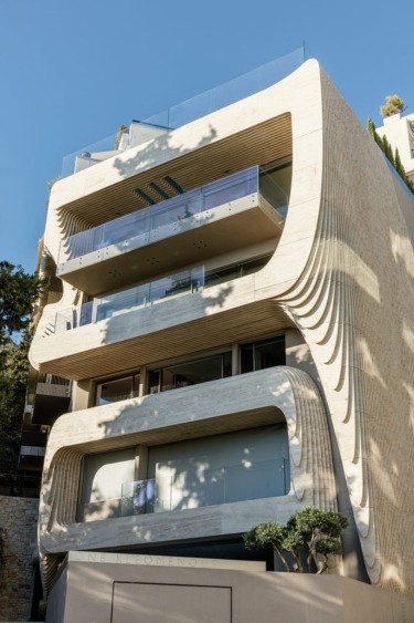 The building is situated between the wooded Lycabettus hill, trees, and Athens’ typical pale stone structures. Deep balconies have been built on nearly every floor so as to extend the interior spaces. The swimming pool is on the top level.