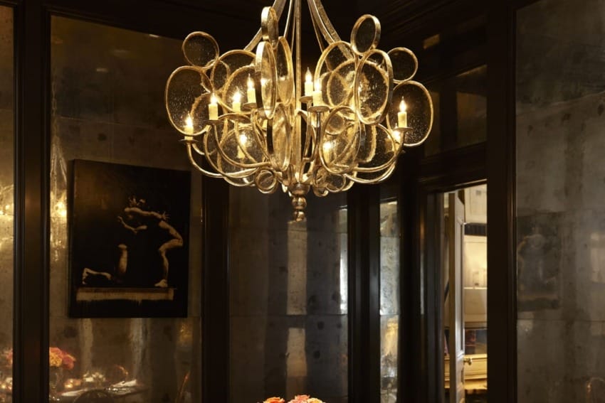 Elegant dining room with a round table, colorful flower centerpiece, and a luxurious chandelier casting warm light.