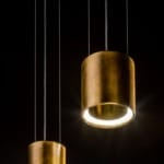 Two elegant, cylindrical pendant lights with a metallic finish hanging against a dark background.