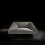 Modern angular gray sofa against a dark background.