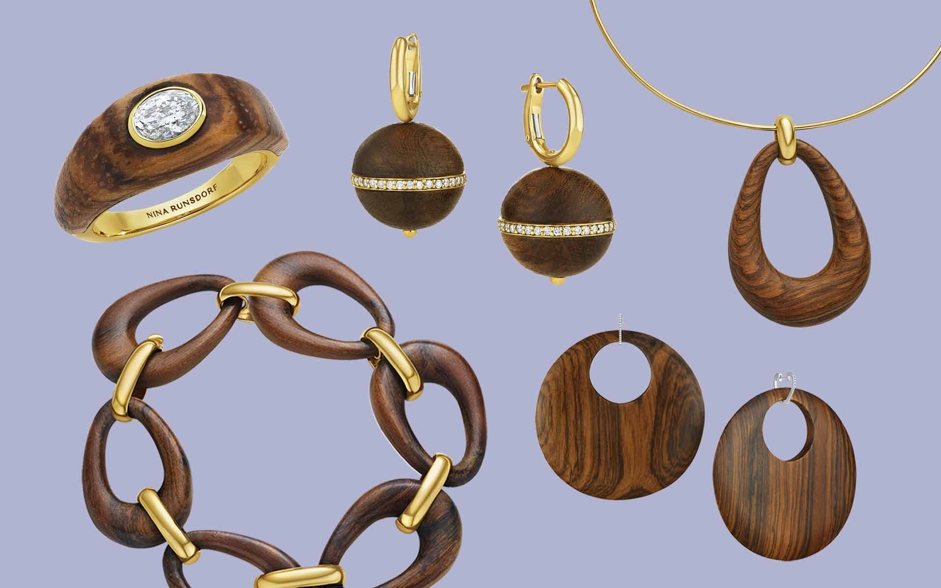 Collection of wooden and gold jewelry including rings, earrings, a bracelet, and a necklace on a light blue background.