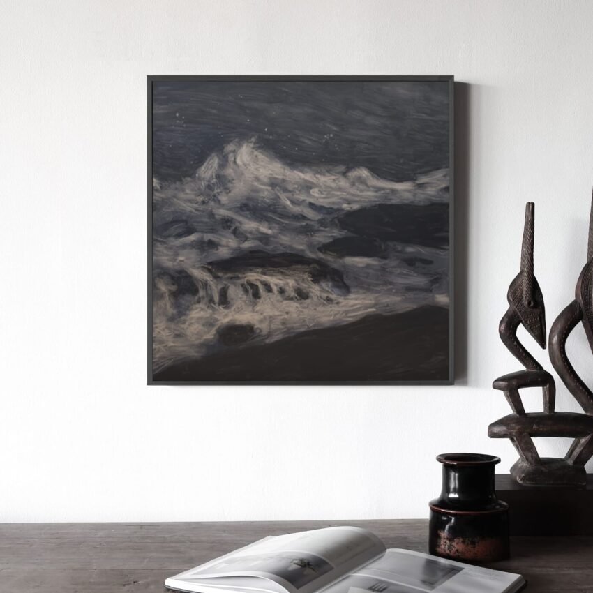 Framed abstract painting of ocean waves on a wall, with sculptures and an open book on a table nearby.