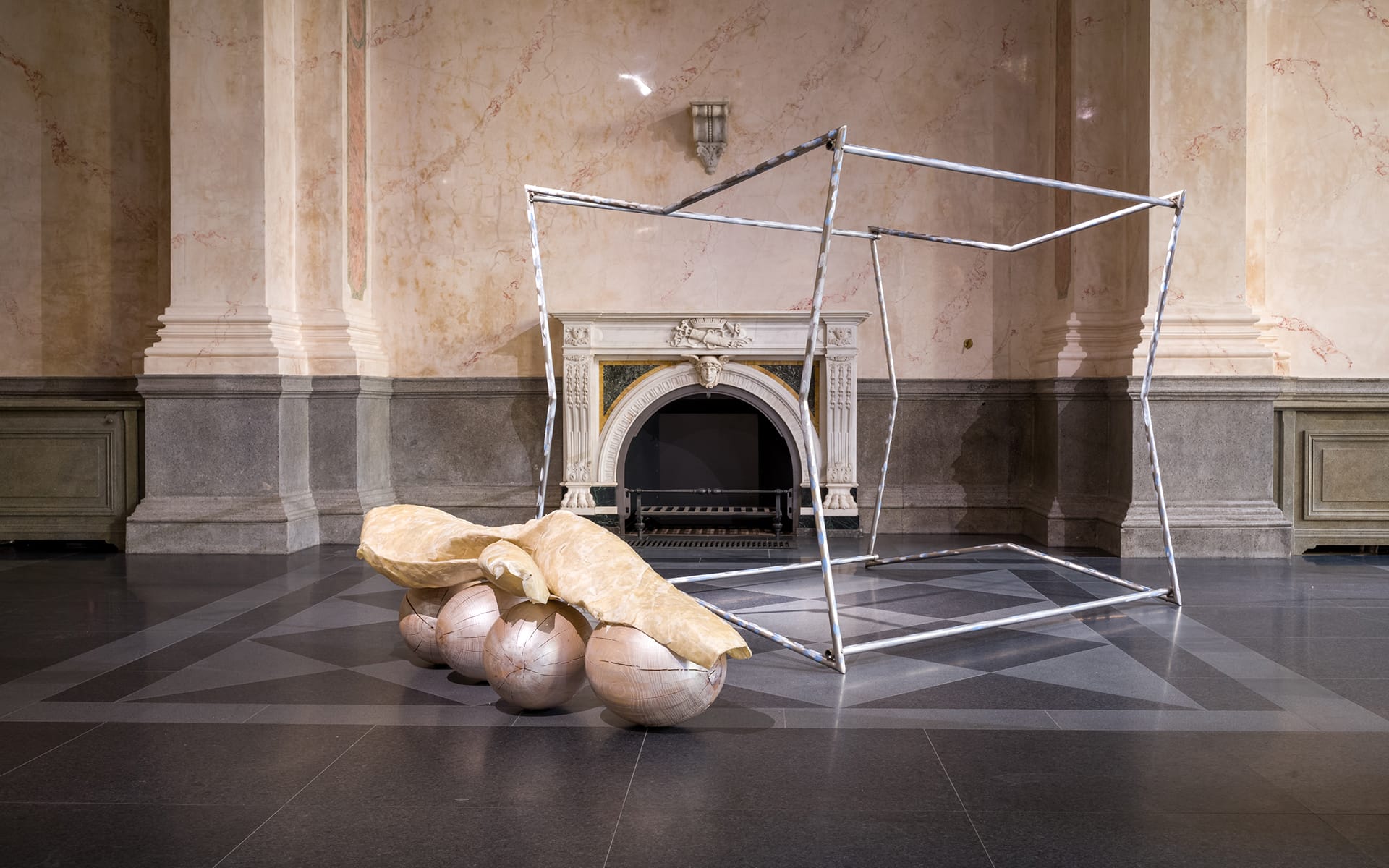 Contemporary art installation with geometric metal frame and organic forms in a classic interior setting.