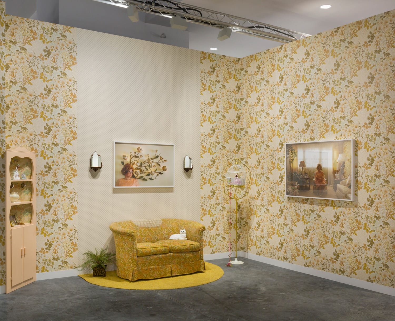 Retro-style living room with floral wallpaper, vintage sofa, wall art, and decorative shelves in a cozy setting.