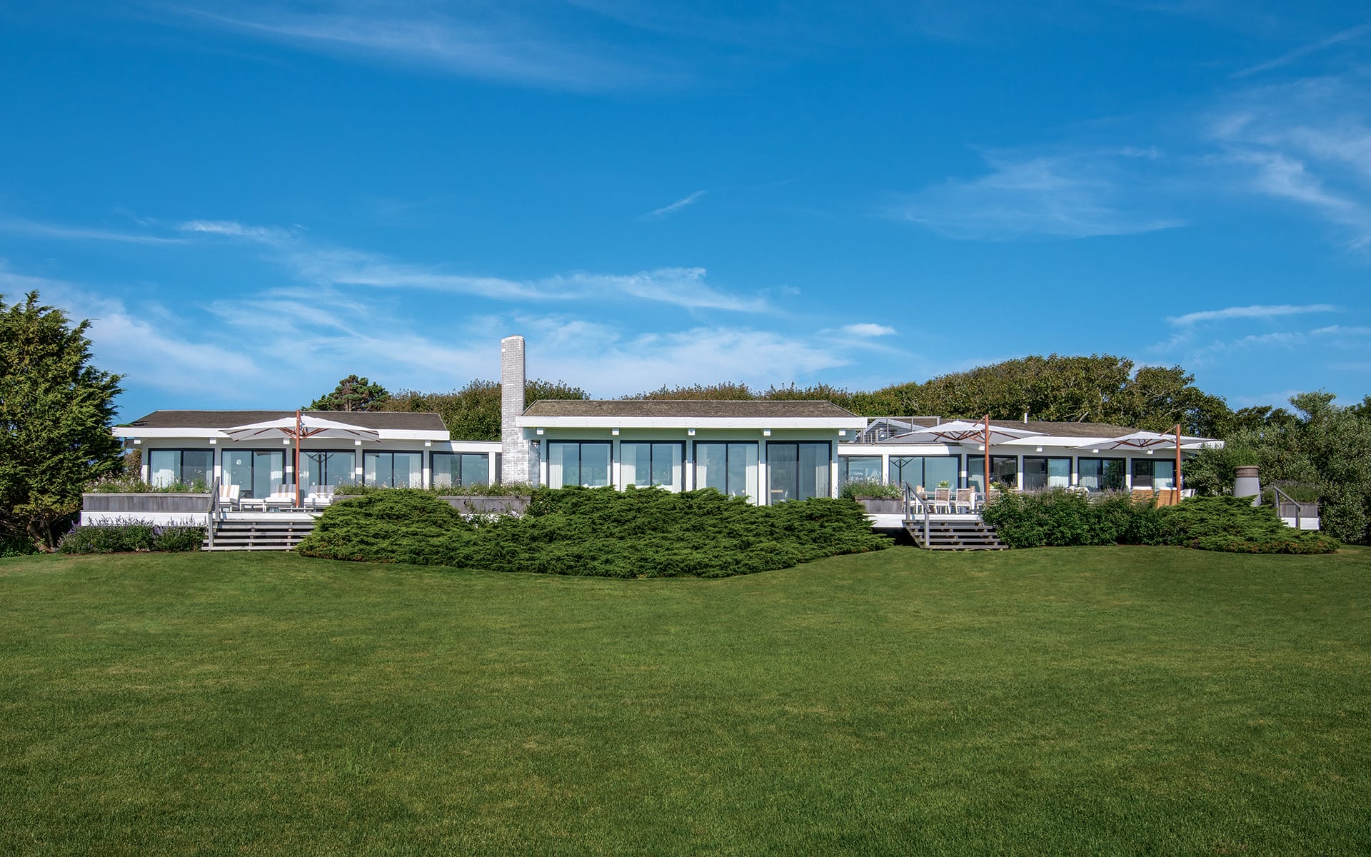 Modern house with large windows and green lawn under a clear blue sky