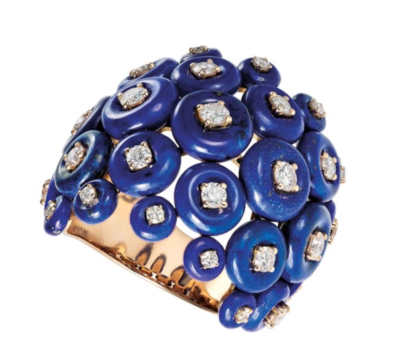 Gold ring adorned with blue circular stones and small diamonds arranged in a unique pattern.