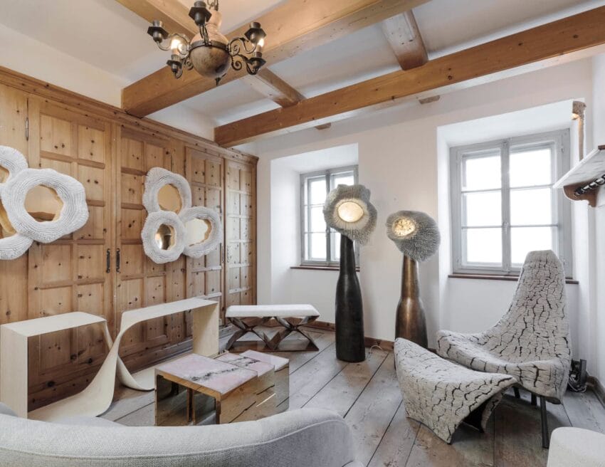 Modern living room with unique wooden furniture, abstract wall art, and large windows allowing natural light to fill the space