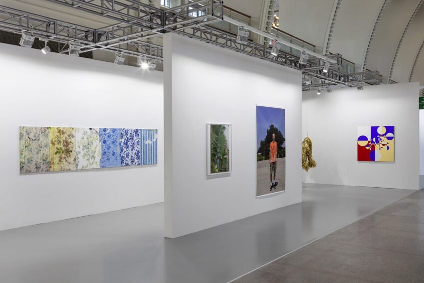 Art gallery interior showcasing various modern paintings on white walls with a smooth gray floor.