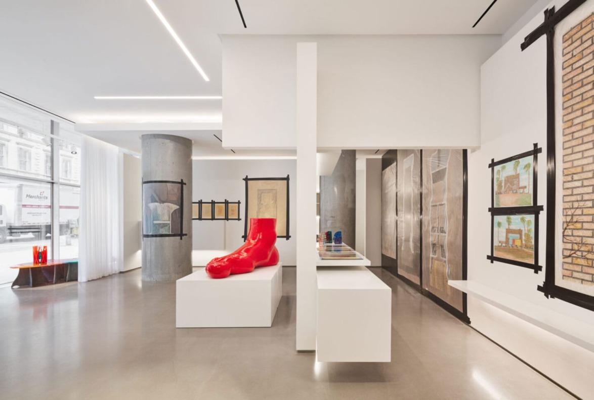 Modern art gallery interior with red boot sculpture, paintings, and sculptures on display, featuring minimalist design.