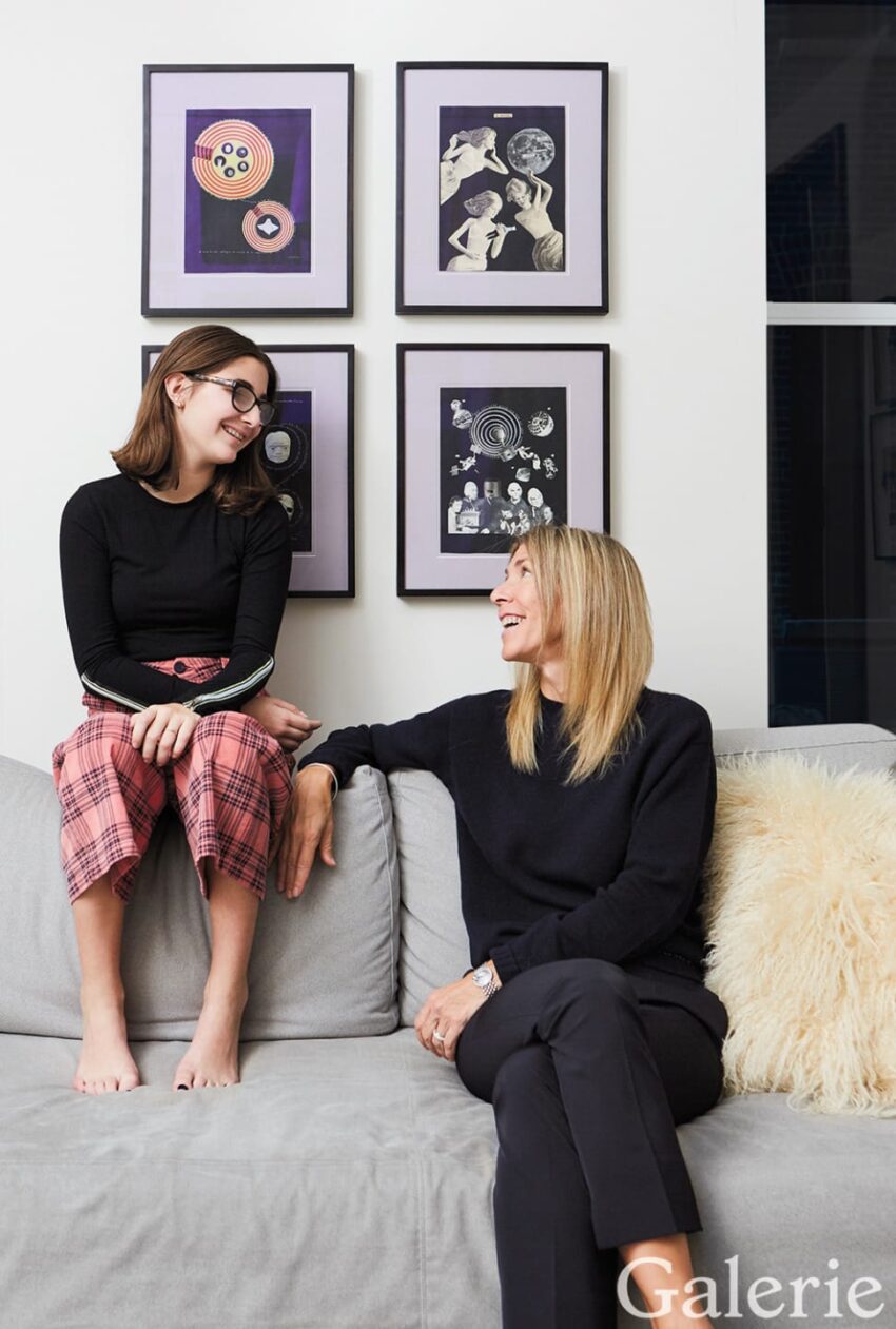 Two people sit and smile in a room with framed art on the wall and a grey couch in a modern living space.