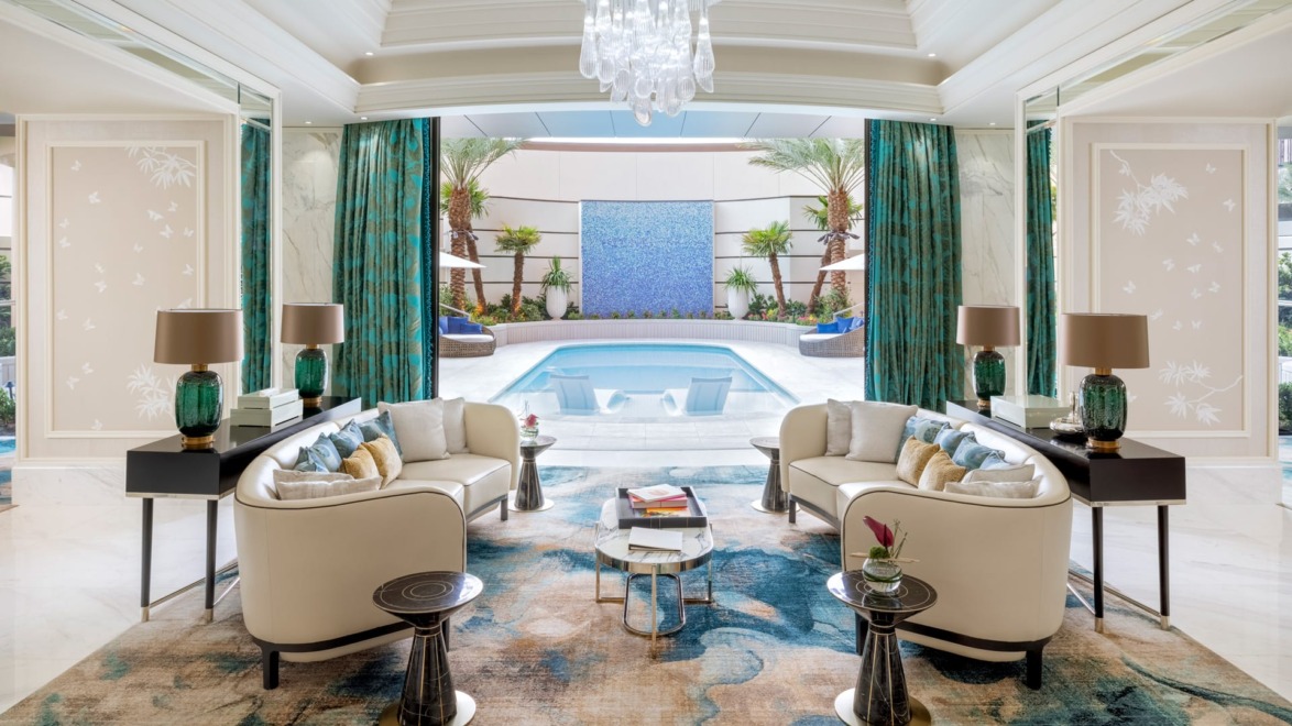 Luxurious living room with elegant sofas, stylish decor, and view of a pool through large glass doors, featuring green accents.